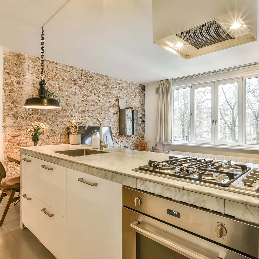 Kitchen with marble island and exposed brick wall